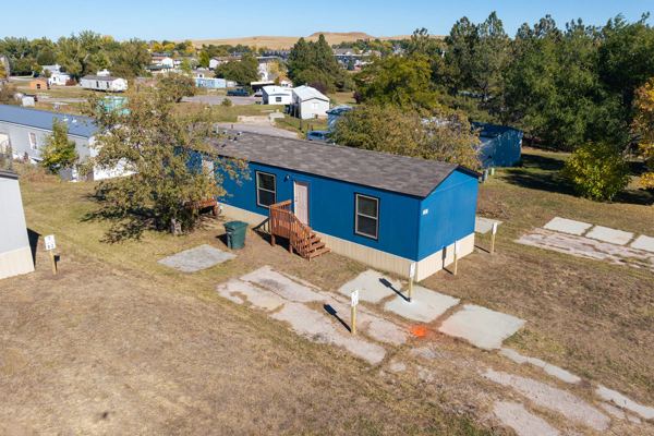 Aerial view of a home on its lot with the park and trees beyond